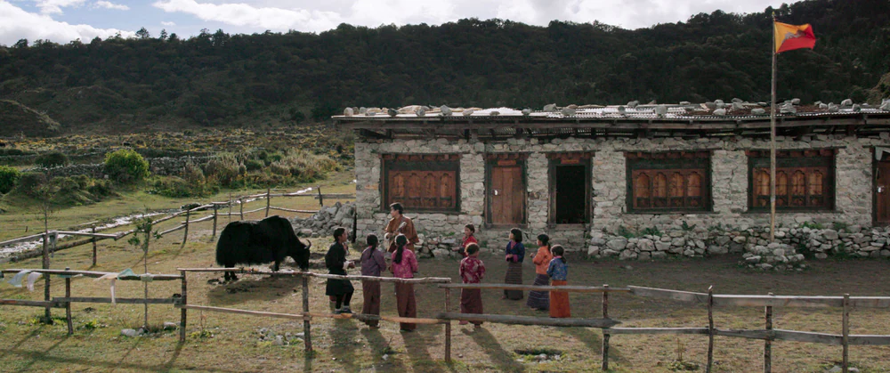 Lunana: Il vilaggio alla fine del mondo: l'esterno della scuola con Sherab Dorji, i suoi piccoli alunni e lo yak